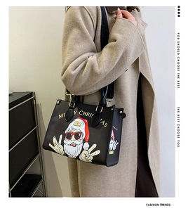 Detailed view of black Christmas tote bag with Santa print and adjustable strap on model