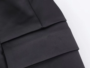 Detail view of black herringbone wool blazer showing pocket flap and fabric texture