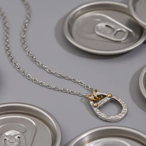 Macro shot of 18K gold and silver two-tone soda tab pendant on a stainless steel chain