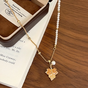 Detail of 18K gold maple leaf pendant with amber zircon and elegant pearl strand