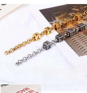 Detail of gold and silver steel chain bracelets with Lucky engraved cube beads