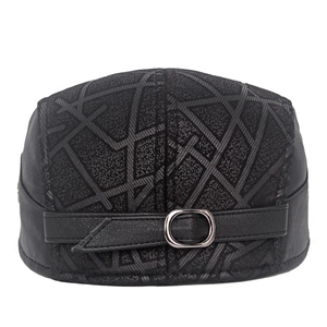 Close-up of black leather flat cap with metal buckle strap and geometric pattern