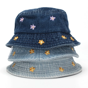 Close-up of stacked denim bucket hats with detailed purple and yellow flower embroidery