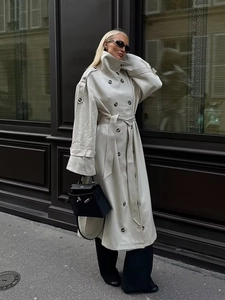 Detail of classic double-breasted cream trench coat with waist belt and epaulettes
