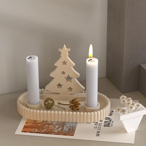 Scalloped tray base featuring a cutout wooden tree stand and white pillar candles