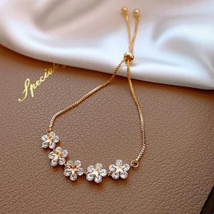 Detail of adjustable gold bracelet with star centers and zircon floral elements