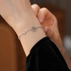 Close-up of silver compass bracelet with yellow gemstone on model's wrist