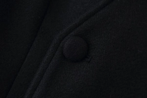 Gros plan détaillé d'un bouton recouvert de tissu noir et d'un mélange de laine