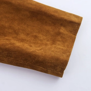 Gros plan sur la texture en daim caramel et les coutures délicates de la veste