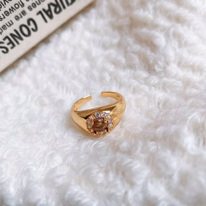 Macro shot of vintage gold ring with oval brown stone and zircon halo on velvet