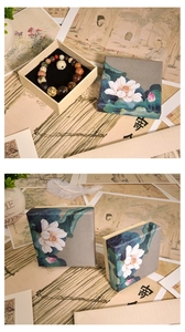 Detail of square vintage Chinese jewelry box with lotus painting and beaded bracelet