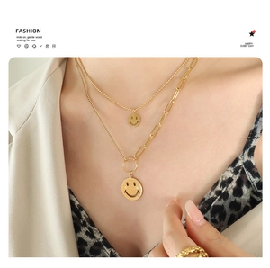 Primer plano de collar dorado de doble capa con colgante de carita sonriente en modelo