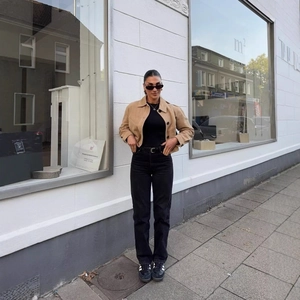 Veste courte chic camel à revers avec jean noir présentée en style urbain extérieur
