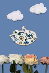Dettaglio macro del vassoio per gioielli in ceramica a forma di mano con motivi a occhio