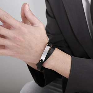 Detail of a men's double-layer black leather bracelet with a polished steel plate on a wrist