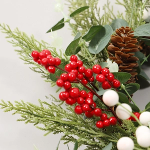 Christmas wreath with red and white berries, natural pinecones, and lush green leaves