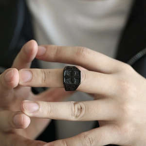 Macro detail of retro black stainless steel cross ring with textured stone finish