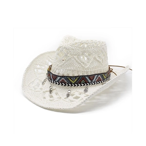Detailed shot of white hollow straw hat with ethnic embroidery and heart pendants