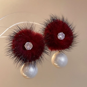 Close-up of wine red pompom earring with zircon center and large white pearl drop