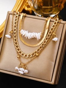Close-up of gold layered necklace with faux pearls on a beige jewelry box backdrop