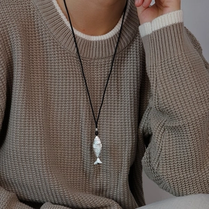 Detailed view of silver fish pendant with intricate scales on black woven cord