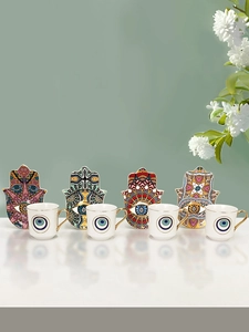 Detail of ceramic espresso cup sets with blue evil eye motifs and Hamsa shaped saucers