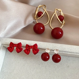 Close-up of vintage red pearl earring set with bows and beads on silk background