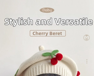 Close-up of cream knit baby beret with 3D red cherry crochet appliqué detail