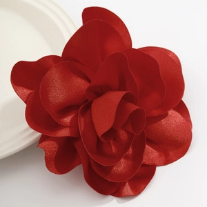 Detailed close-up of a vibrant red layered fabric flower brooch with silk-like texture