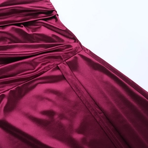 Vue macro d'une robe en satin bordeaux montrant les plis élégants et les détails du tissu