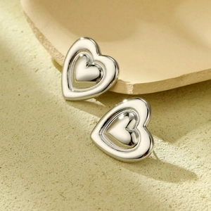 Macro shot of silver nested double heart stud earrings in polished stainless steel