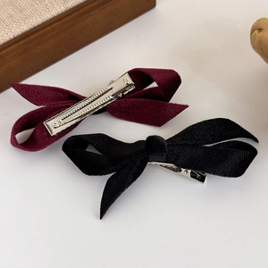 Close-up of velvet bow hair clips in wine red and black with silver alligator clips
