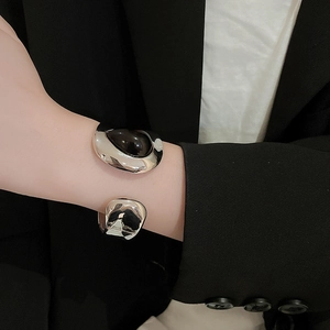Detail of wide silver metal cuff with large black teardrop stone on a female model