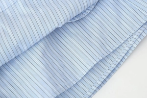 Macro shot of blue fine striped cotton fabric detail and double stitching of the shirt