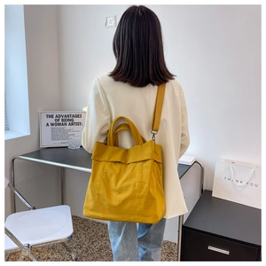 Rear view of a yellow nylon tote bag on a model showing large capacity and casual style