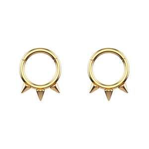 Detailed view of golden punk style circular barbell rings with three sharp cone spikes