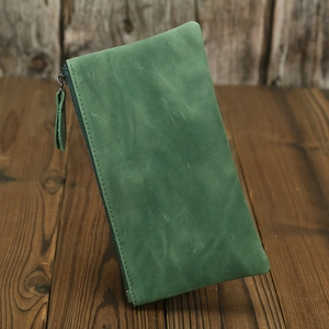 Close-up of a green distressed crazy horse leather wallet on a rustic wooden table