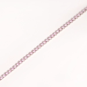 Macro detail of pink zircon tennis chain featuring classic claw setting on silver metal