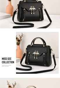 Detail of black textured crossbody bag with golden swan heart hardware and top handle