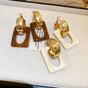 Detailed macro view of geometric resin drop earrings in amber brown and cream white finish