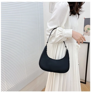 Minimalist black crescent shoulder bag shown on model with sleek nylon texture details