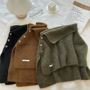 Detail of high-neck knitted shawls in black, brown, and green with decorative buttons