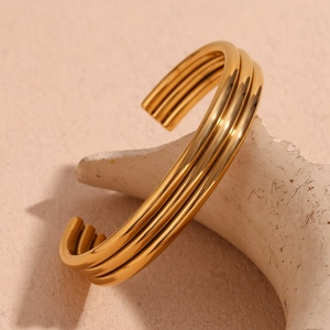 Macro shot of 18K gold plated three-layer stainless steel cuff bracelet on beige display