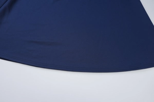 Detailed close-up of the curved hemline and double-stitched sewing on the navy dress