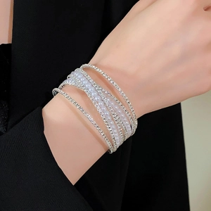Detail van een meerlagige wikkelarmband met witte parels en kristallen op zilveren basis