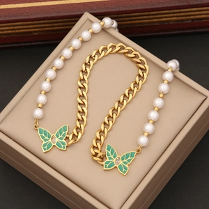 Collier de perles dorées avec pendentif papillon vert sur une boîte à bijoux beige