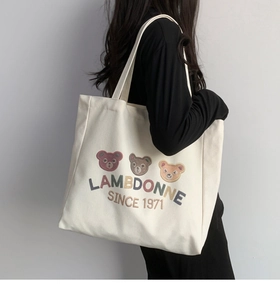 Lifestyle shot of a white canvas tote bag with colorful bears carried by a model