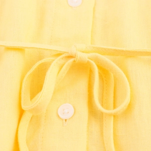 Detail of yellow linen shirt fabric showing a decorative bow tie and white round buttons