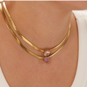 Close-up of double-layer gold snake chains with heart-cut white and purple zirconia