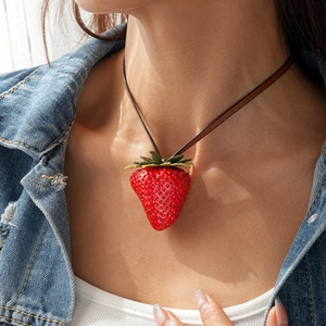 Detail of red resin strawberry pendant with green leaves on brown leather cord necklace